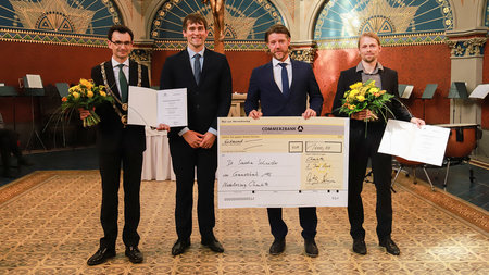 Rektor und Commerzbank-Vertreter überreichen symbolischen Scheck an die Preisträger