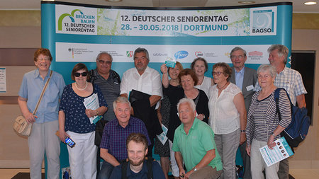 Gruppenfoto der Teilnehmenden des Seniorenkollegs vor einer Messewand 