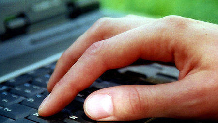 Eine Hand drückt Tasten auf einer Tastatur.