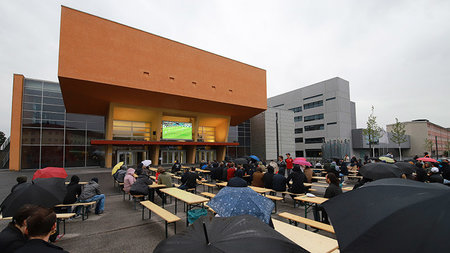 Fußballfans sitzen vor dem Hörsaalgebäude und schauen auf der LED-Wand das Spiel gegen Schweden