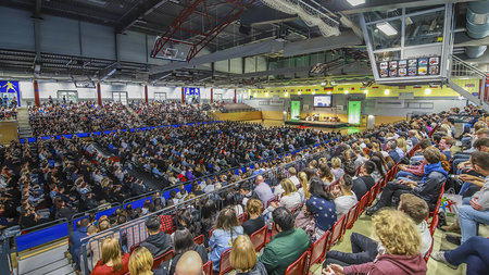 Viele Mensche sitzen in der Hartmannhalle auf den Rängen und auf Stuhlreihen