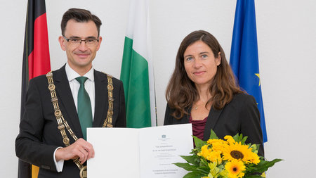 Frau und Mann mittleren Alters mit Urkunde.