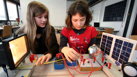 Zwei Mädchen experimentieren mit einer Solarzelle.