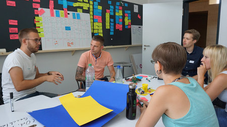 Studierende diskutieren vor einer Tafel miteinander