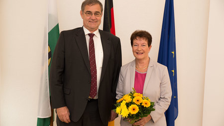 Ein Herr steht neben einer Frau mit Blumenstrauß