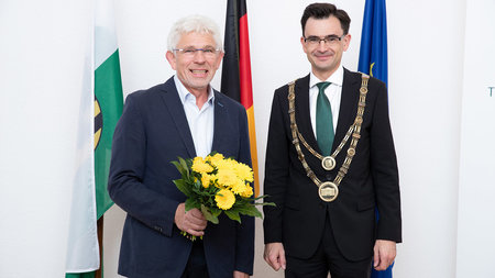 Rektor steht neben Professor Wanielik, der einen Blumenstrauß in der Hand hält