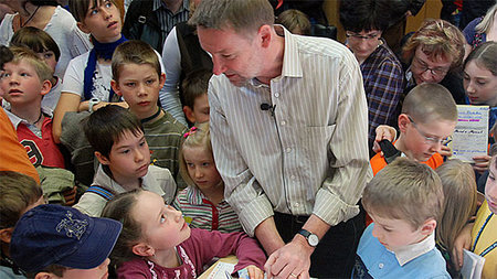 Dr. Thomas Bührke spricht im Hörsaal mit Kindern.
