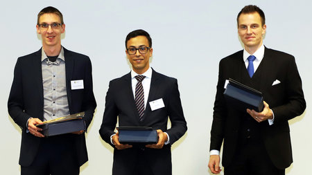 Drei Preisträger halten Urkunden in ihren Händen.