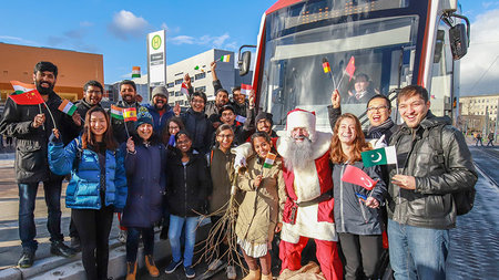 Nikolaus und Studierende stehen vor einer Straßenbahn auf dem Campusplatz