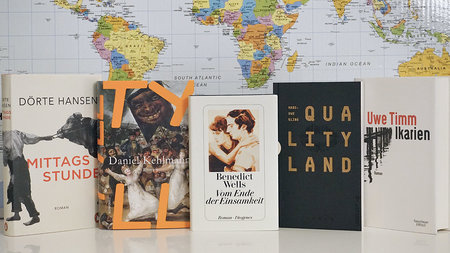 Fünf Bücher stehen vor einer Weltkarte.