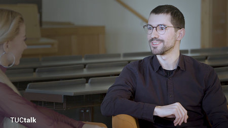 Ein junger Mann mit Brille lächelt.