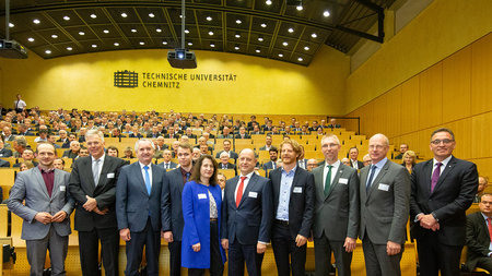 Gruppe steht vor einem voll besetzten Hörsaal.