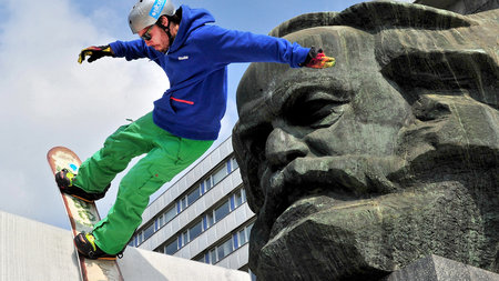 Mann fährt neben dem Marx-Monument in Chemnitz mit Snowboard eine Rampe hinunter