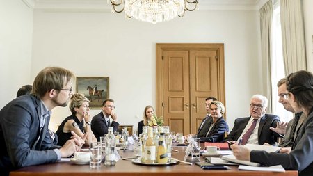 Mehrere Personen sitzen am Tisch und reden miteinander.