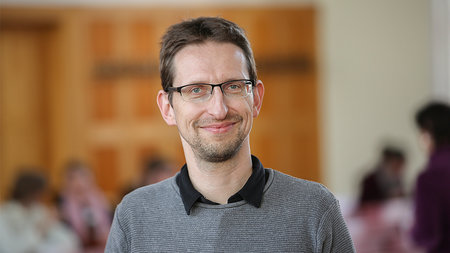 Jüngerer Mann lächelt.