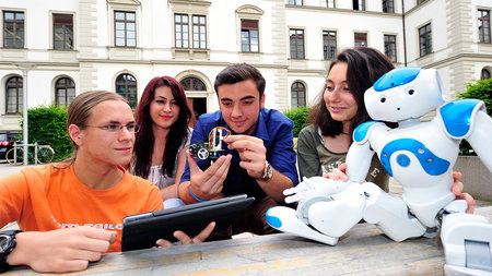 Vier junge Leute mit einem Roboter