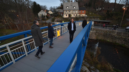 Drei Personen laufen über eine Brücke