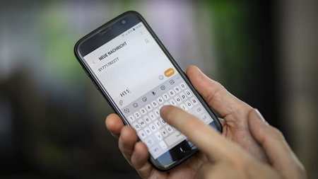 Smartphone liegt in einer Hand, mit einem Finger wird Textfolge H11 getippt.