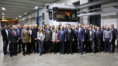 Viele Personen stehen in einer Werkhalle vor einem Truck.