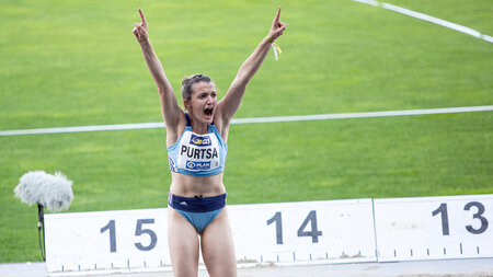 Frau sitzt am Rand eines Sportplatzes