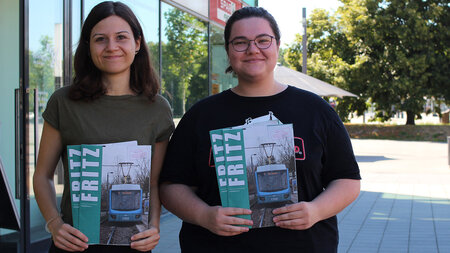 Zwei Frau halten Zeitschriften in der Hand. 