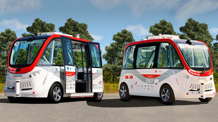 Two small self-driving shuttles sit in a parking lot.