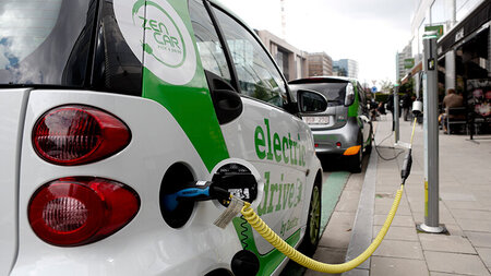 Ein Elektroauto ist mit einem Kabel mit einer Ladesäule verbunden.