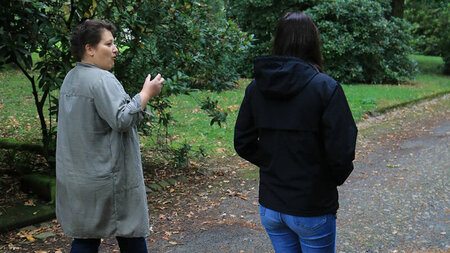 Zwei Frauen laufen im Park nebeneinander.