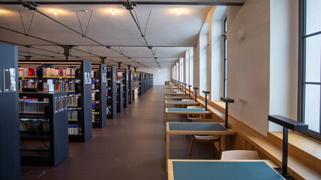 Blick auf zahlreiche Bücherregale und hintereinander angeordnete Leseplätze.