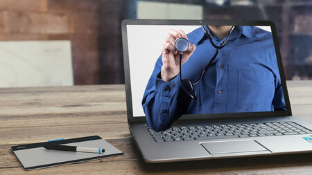 Ein Laptop mit dem Bild eines Arztes, der ein Stetoskop hält.