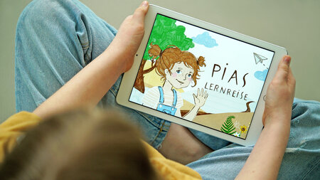 Ein Tablet auf dem Lern-App Pias Lernreise läuft.