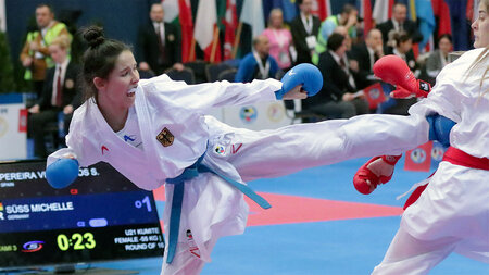 Eine junge Frau im Karateanzug führt einen Kick aus.