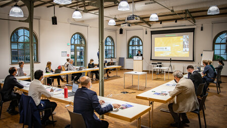 Teilnehmerinnen und Teilnehmern an einem Workshop hören einem Redner zu.