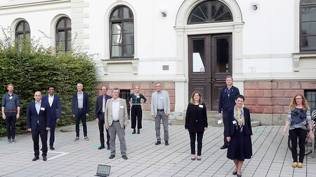 Eine Gruppe von Personen steht mit Abstand nebeneinander.