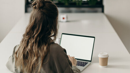 Eine junge Frau sitzt an einem Laptop.