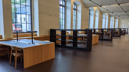 Schreibtische stehen versetzt zueinander in einem großen Raum.