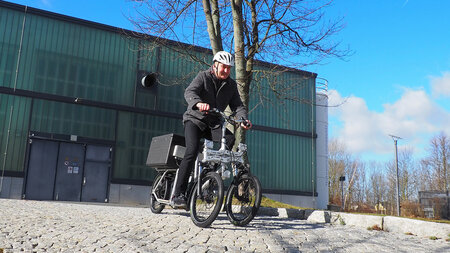 Ein Mann fährt mit einem Lastenfahrrad einen Hang hinunter.