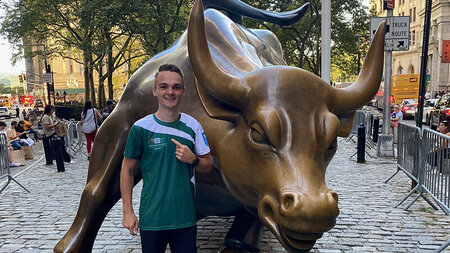 Junger Mann im Lauf-Shirt steht neben einer Bronzestatue in der Grestalt eines Büffels.