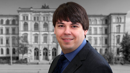 Ein junger Mann im Anzug lacht.