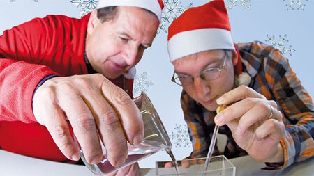 Zwei Männer im Weihnachtsmannkostüm stochern in einem Glas herum.