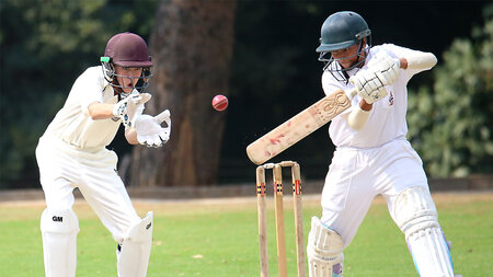 Eine jung Frau und ein junger Mann spielen Cricket.