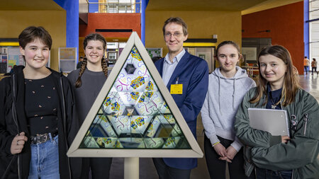 Ein Mann und vier Schülerinnen stehen an einem Pyramiden-Kaleidoskop.