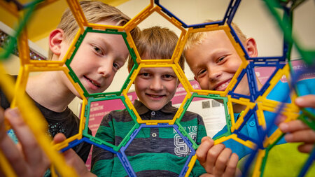 Drei Kinder schauen durch eine Mathematische Form. 