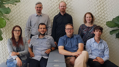 Gruppenfoto von sieben Personen, von denen drei stehen und vier vor ihnen sitzen. 