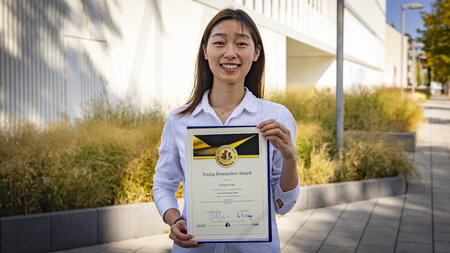A young asian woman holds a certificate.