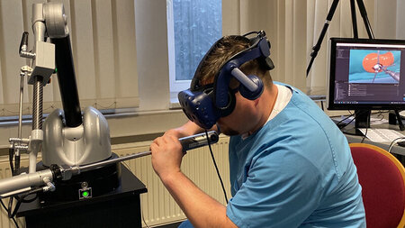 Ein Mann trägt eine VR-Brille und interagiert mit seinen Händen mit einem technischen Gerät.