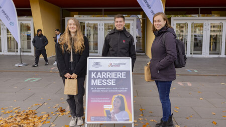 Zwei junge Frauen und ein jugner Mann stehen vor dem Hörsaalgebäude der TU Chemnitz.