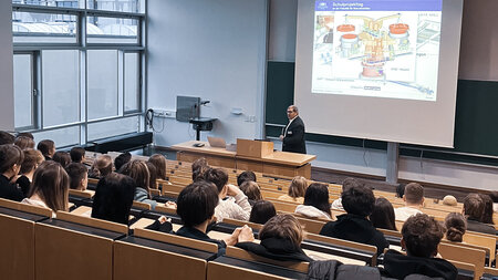 Ein Mann spricht in einem Hörsaal zu Schülerinnen und Schülern.