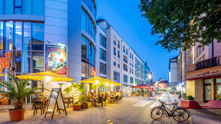 Blick in eine beleuchtete Straße mit Gaststätten.
