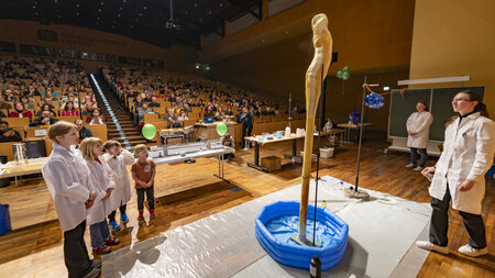 In einem vollbesetzten Hörsaal wird ein chemisches Experiement gezeigt. 